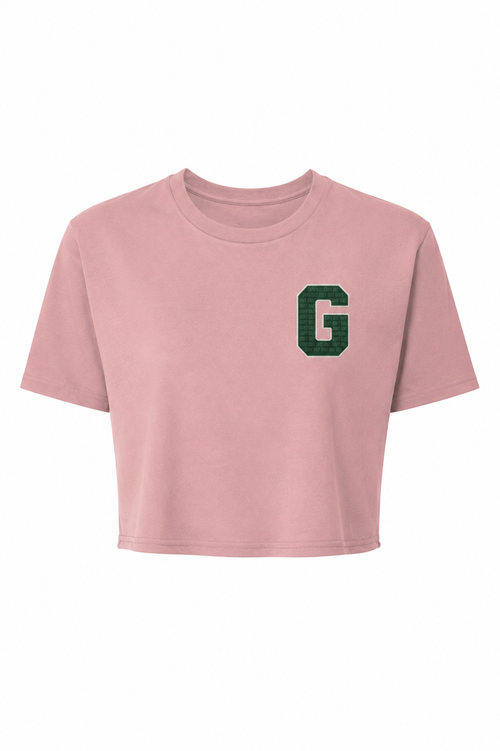 A dusty gripit golf pink short-sleeve crop top t-shirt featuring a textured green block letter 'G' on the left chest, displayed against a solid white background.